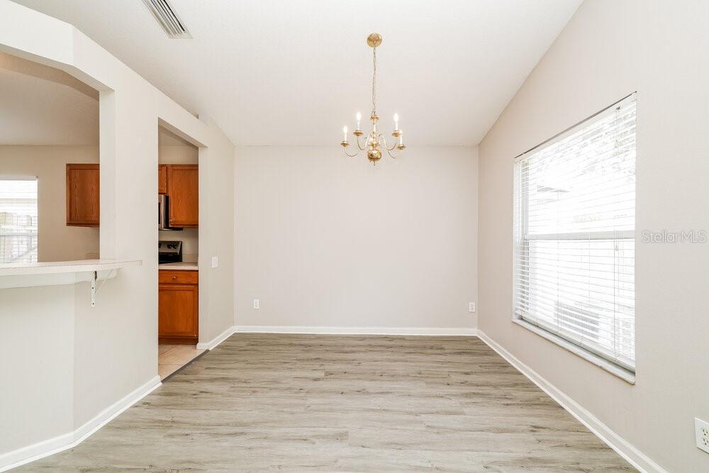 A dining room with light walls, wood-look flooring, and a central chandelier — 10422 HUNTERS HAVEN BOULEVARD, RIVERVIEW, FL