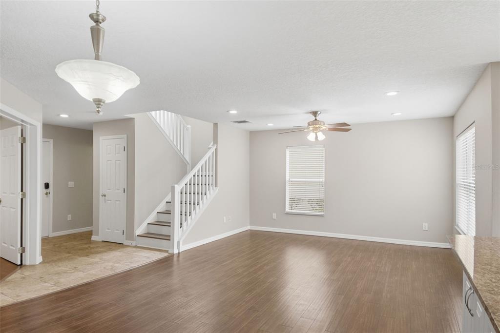 A living room with wood-look flooring, a staircase, a ceiling fan, and a pendant light — 13012 AUBURN COVE LN, ORLANDO, FL