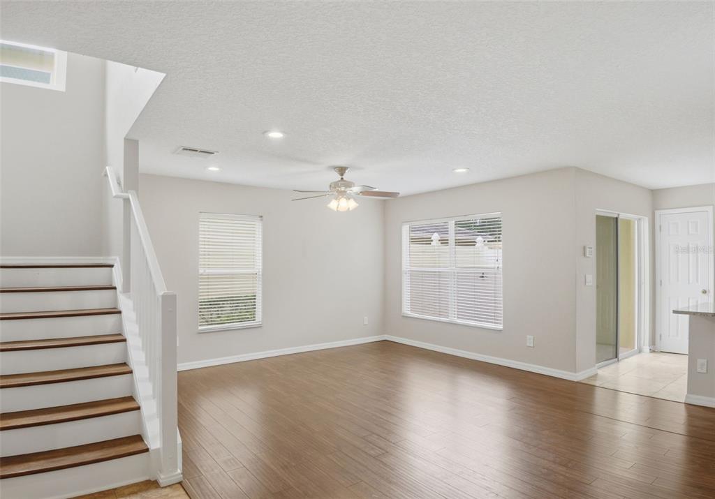 A living room with wood-look flooring, a staircase, and a ceiling fan — 13012 AUBURN COVE LN, ORLANDO, FL