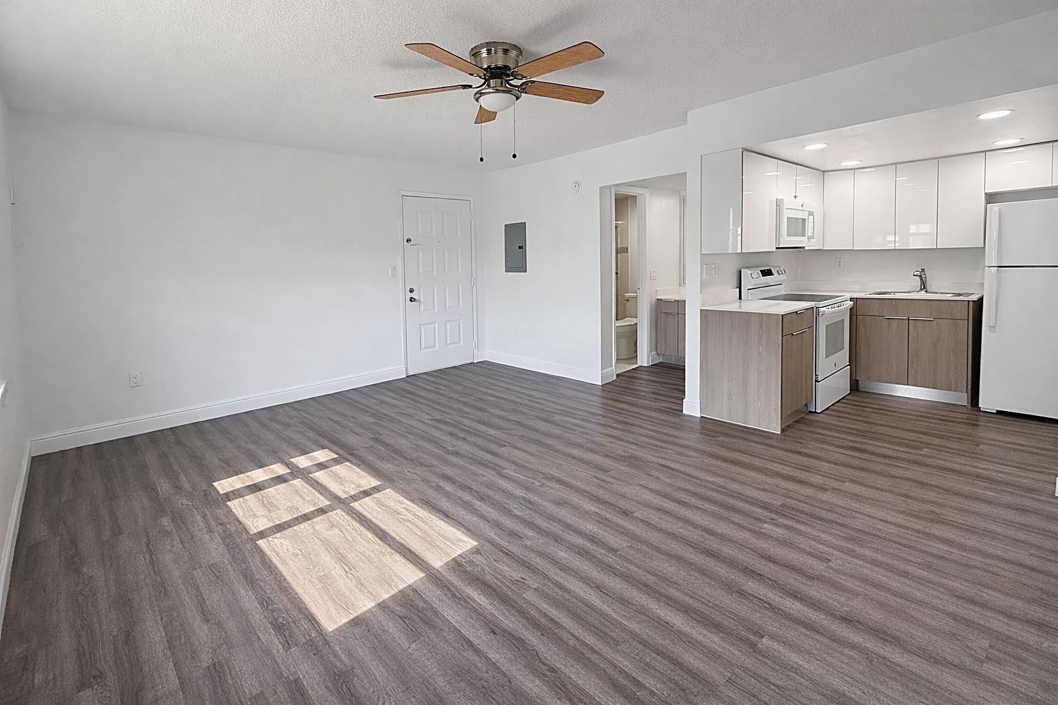 An open-concept living area features wood-look flooring, white walls, a ceiling fan, and a kitchen — 17350 NW 68th Avenue # 402a, Hialeah FL 33015, HIALEAH, FL