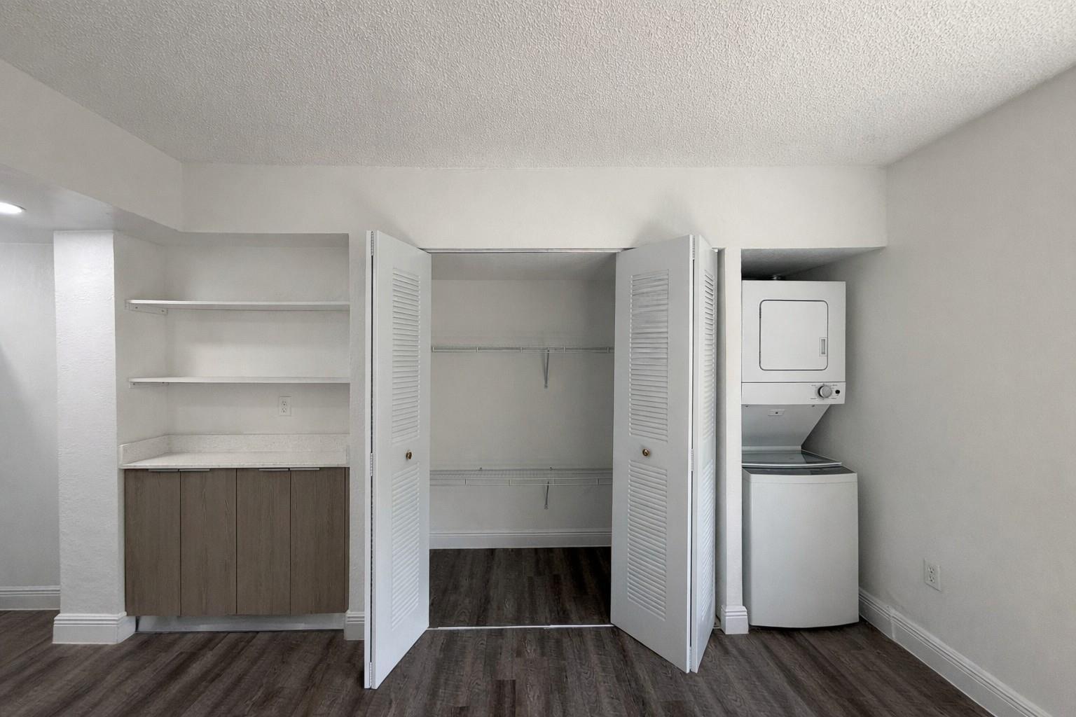 A room features a closet, a stacked washer and dryer, and built-in shelving with cabinets — 17350 NW 68th Avenue # 402a, Hialeah FL 33015, HIALEAH, FL