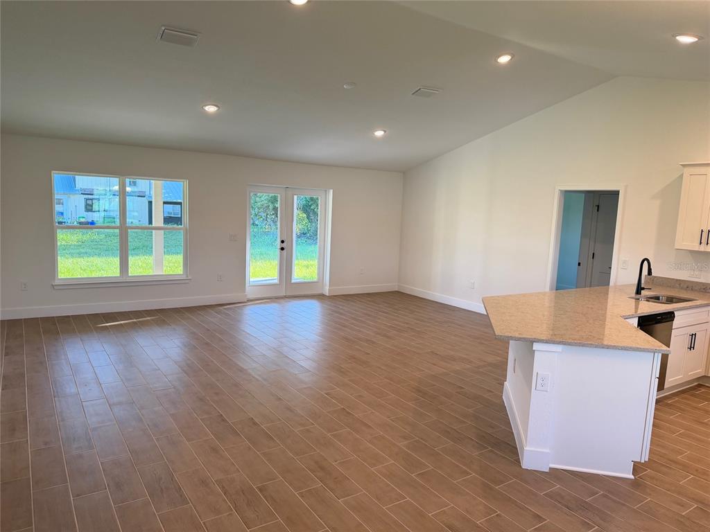 An open-concept living area features wood-look tile flooring, recessed lighting, and a kitchen island — 1252 FLEETWOOD DRIVE, PORT CHARLOTTE, FL