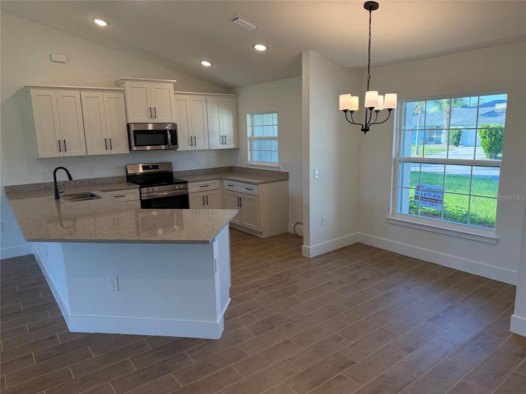 A kitchen with white cabinets, granite countertops, and a dining area with a chandelier — 1252 FLEETWOOD DRIVE, PORT CHARLOTTE, FL