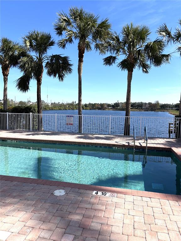 A swimming pool with a brick deck overlooks a lake lined with palm trees — 3825 45TH TERRACE W UNIT 104, BRADENTON, FL
