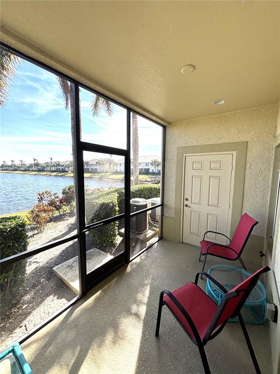 A screened-in patio features two red chairs, a small table, and a view of water — 3825 45TH TERRACE W UNIT 104, BRADENTON, FL