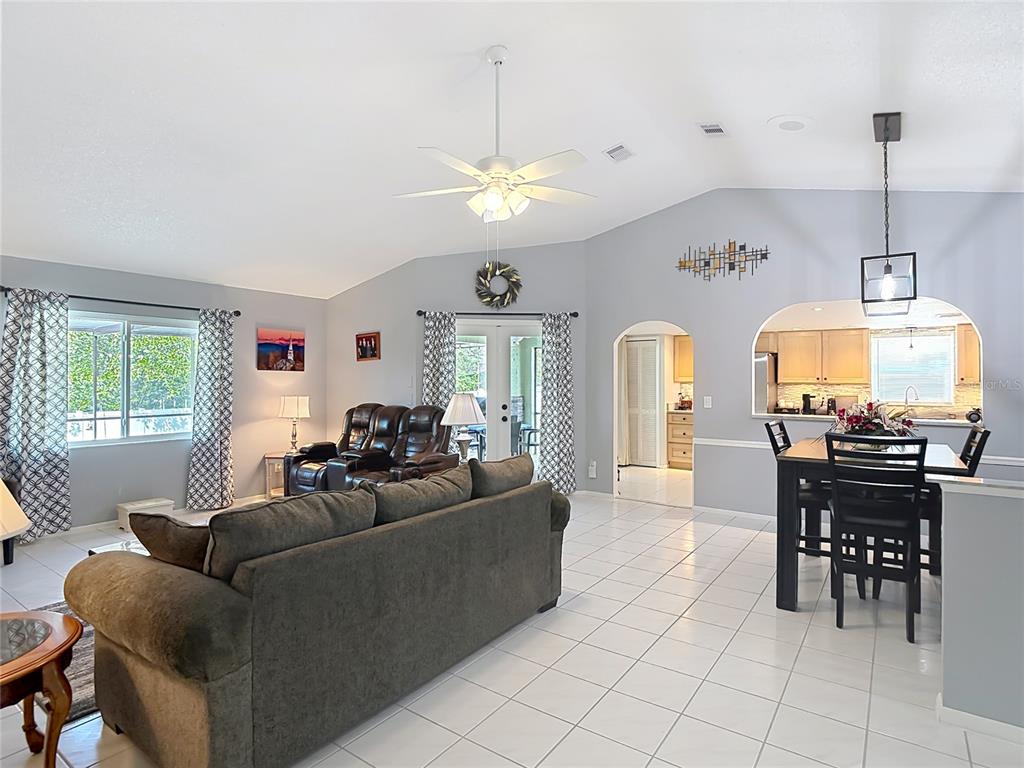 A living room and dining area feature vaulted ceilings, tile flooring, and an open kitchen — 11382 PICKFORD STREET, SPRING HILL, FL