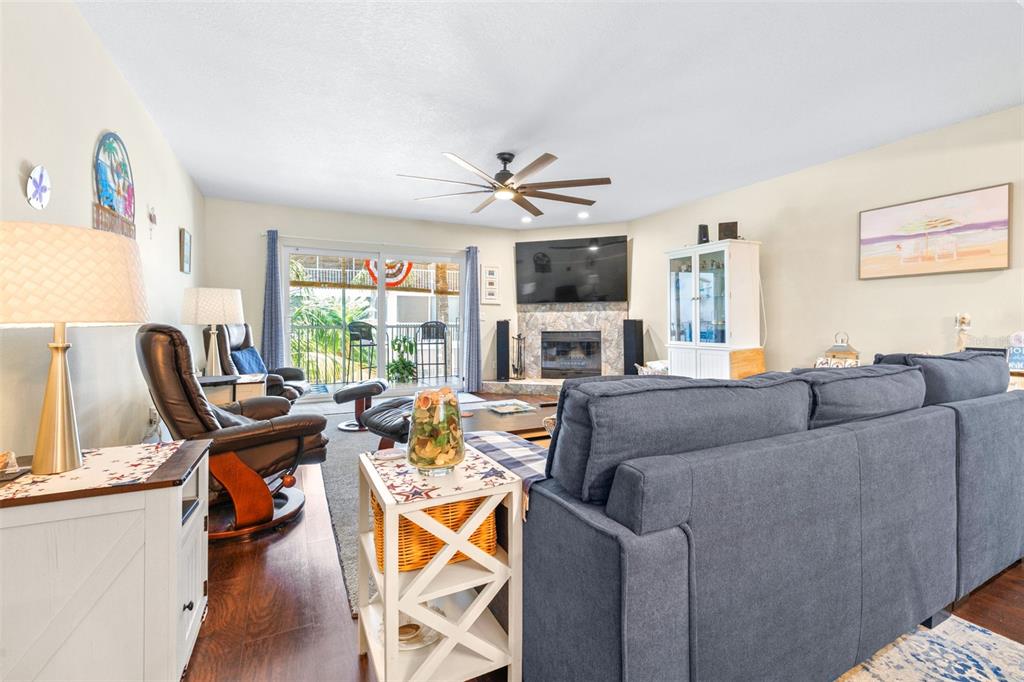 A living room features a blue sectional sofa, a fireplace, and a sliding glass door — 751 PINELLAS BAYWAY S UNIT 208, TIERRA VERDE, FL