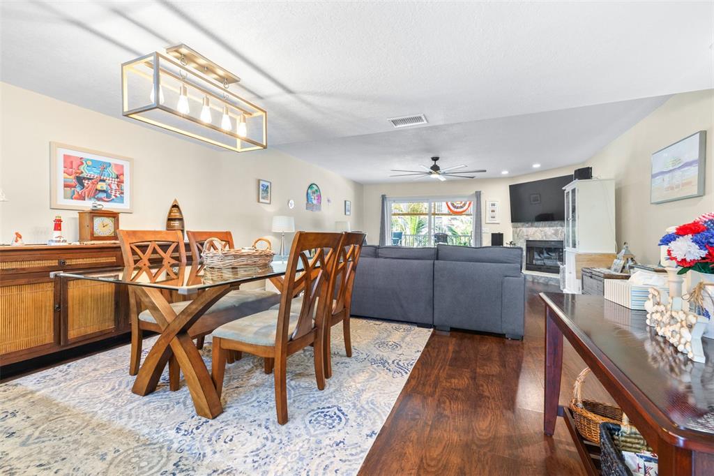 A dining area with a glass-top table sits in front of a living room with a fireplace — 751 PINELLAS BAYWAY S UNIT 208, TIERRA VERDE, FL