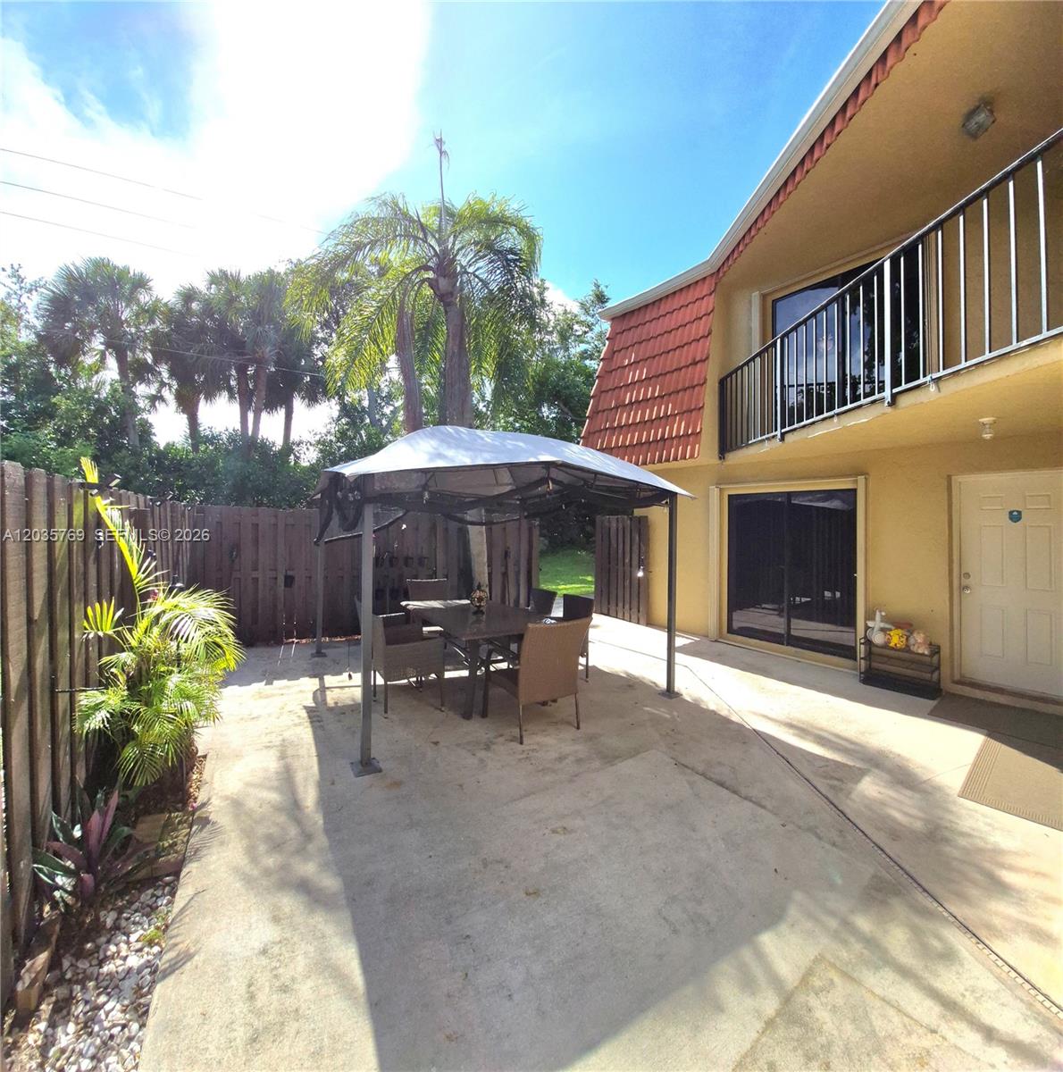 A concrete patio features a metal gazebo with outdoor furniture next to a two-story house — 23106 Oxford Pl # D, Boca Raton FL 33433, BOCA RATON, FL