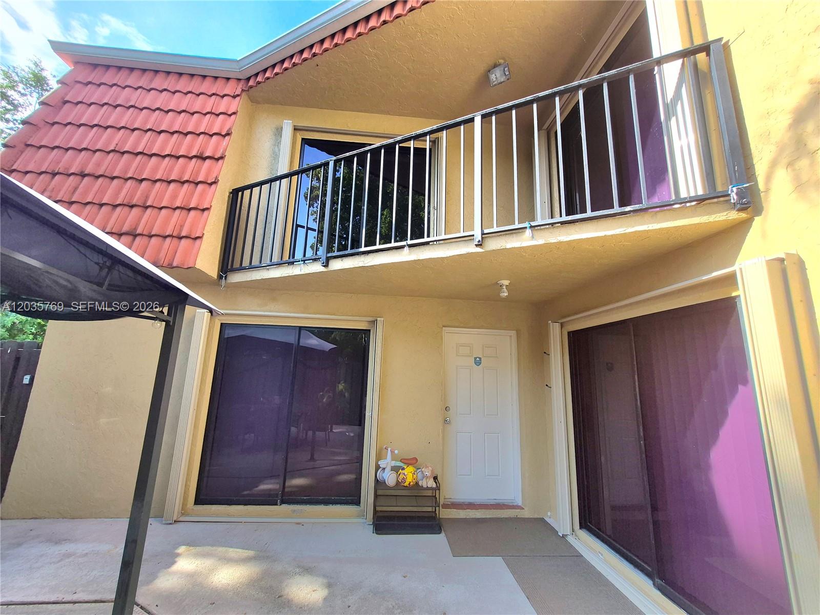 The exterior of a two-story home features a balcony, sliding glass doors, and a tiled roof — 23106 Oxford Pl # D, Boca Raton FL 33433, BOCA RATON, FL