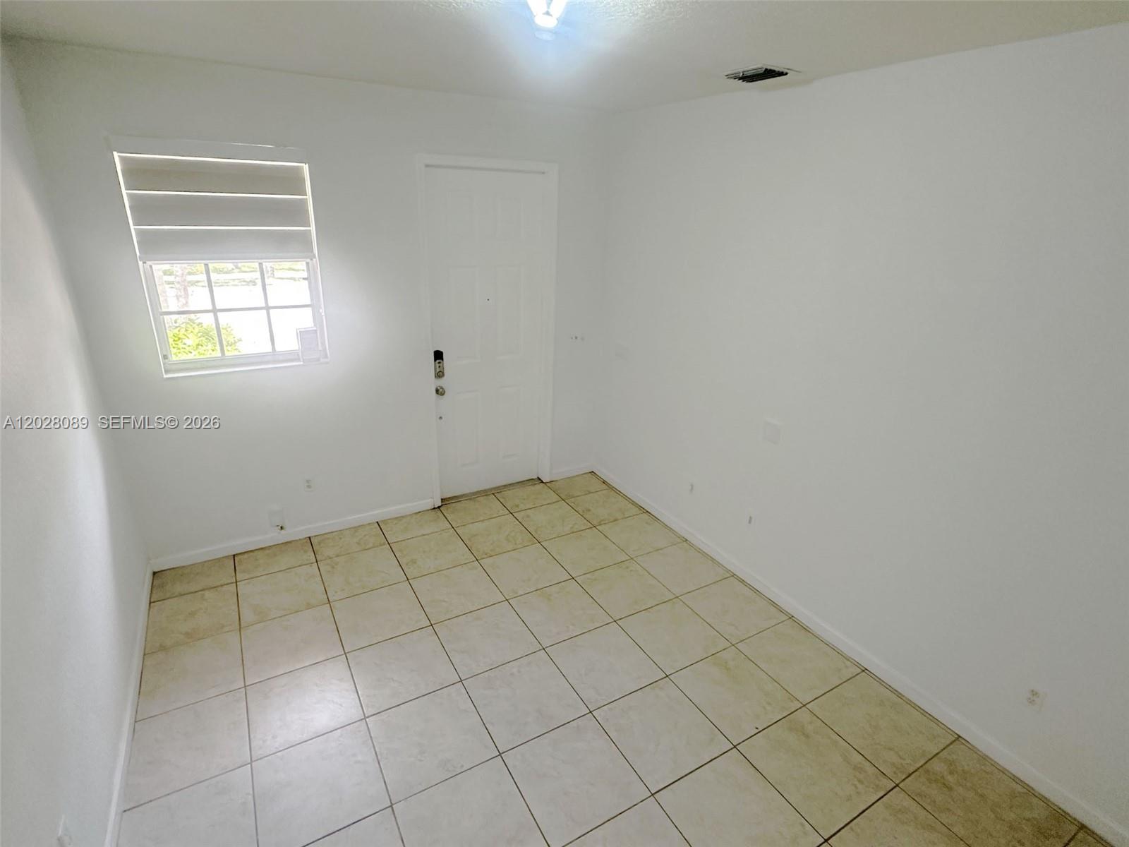 A small, empty room features white walls, a single window, and light-colored tile flooring — 662 NE 21st Ter, Homestead FL 33033, HOMESTEAD, FL