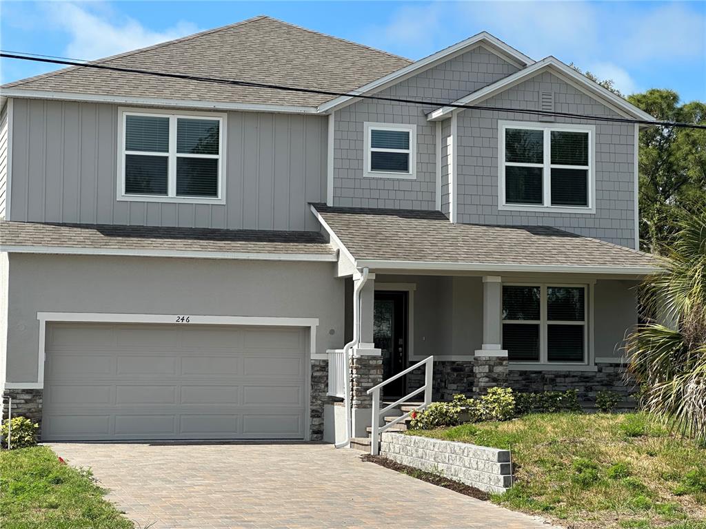 A two-story house with a gray exterior, stone accents, and a paved driveway — 246 BURNEY RD, OSPREY, FL