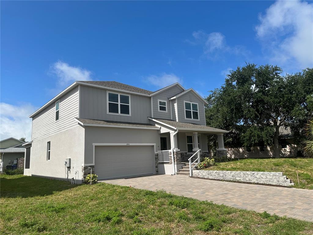 A two-story house with gray siding, a stone-accented facade, and a paved driveway — 246 BURNEY RD, OSPREY, FL