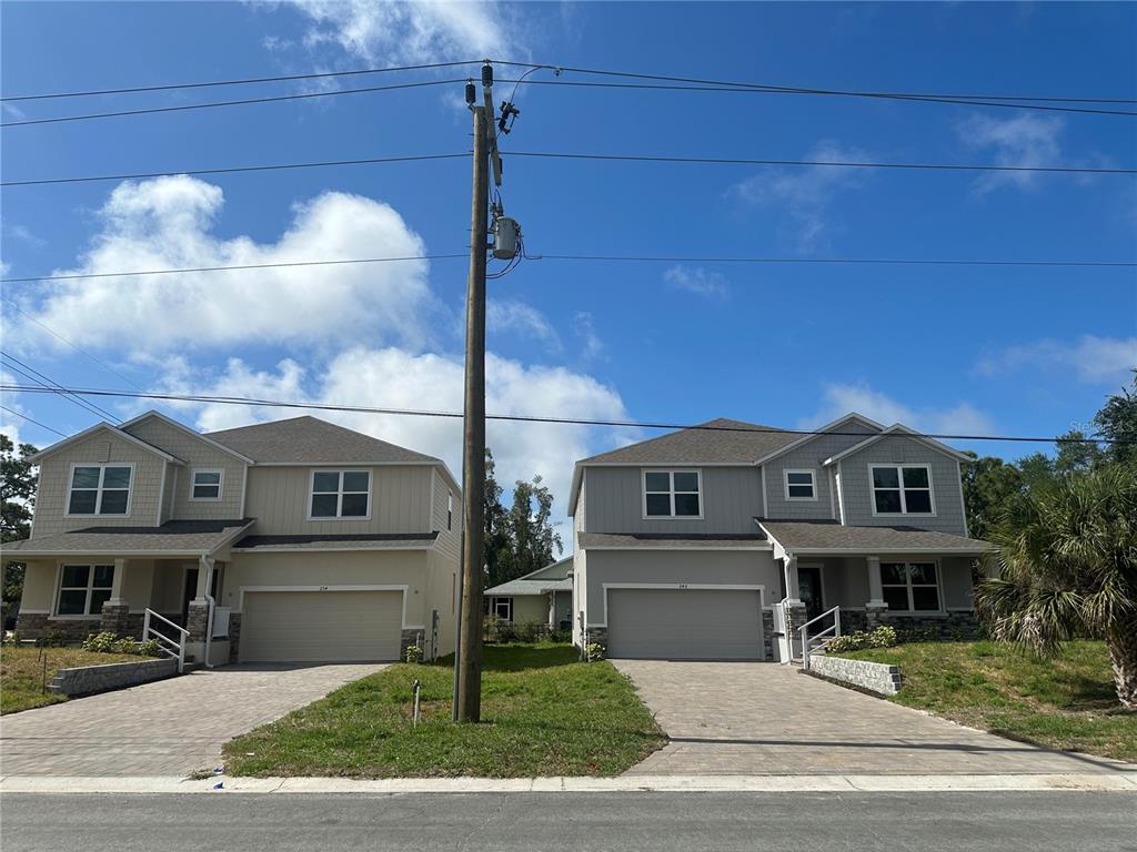 Two identical two-story suburban houses with attached garages stand side-by-side under a blue sky — 246 BURNEY RD, OSPREY, FL