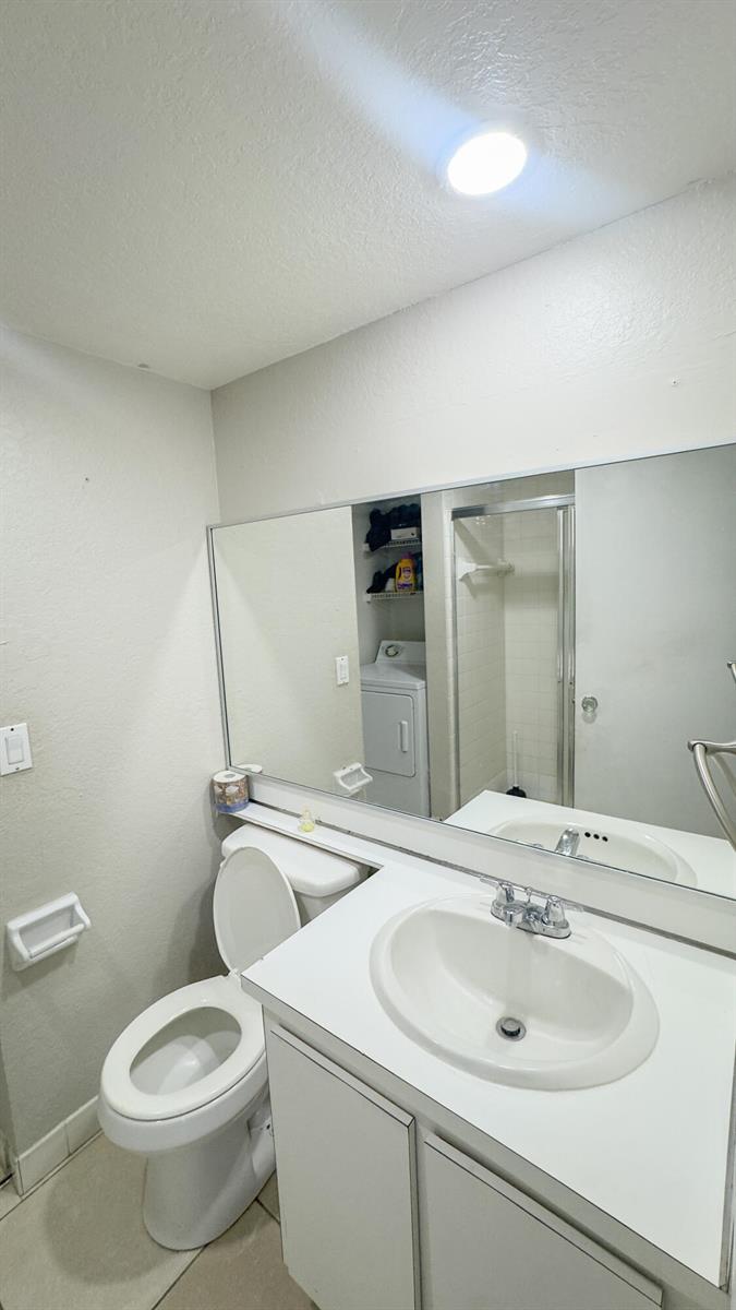 A bathroom features a white vanity with a sink, a toilet, and a large wall mirror — 407 Arabian Road, Palm Springs FL 33461, PALM SPRINGS, FL