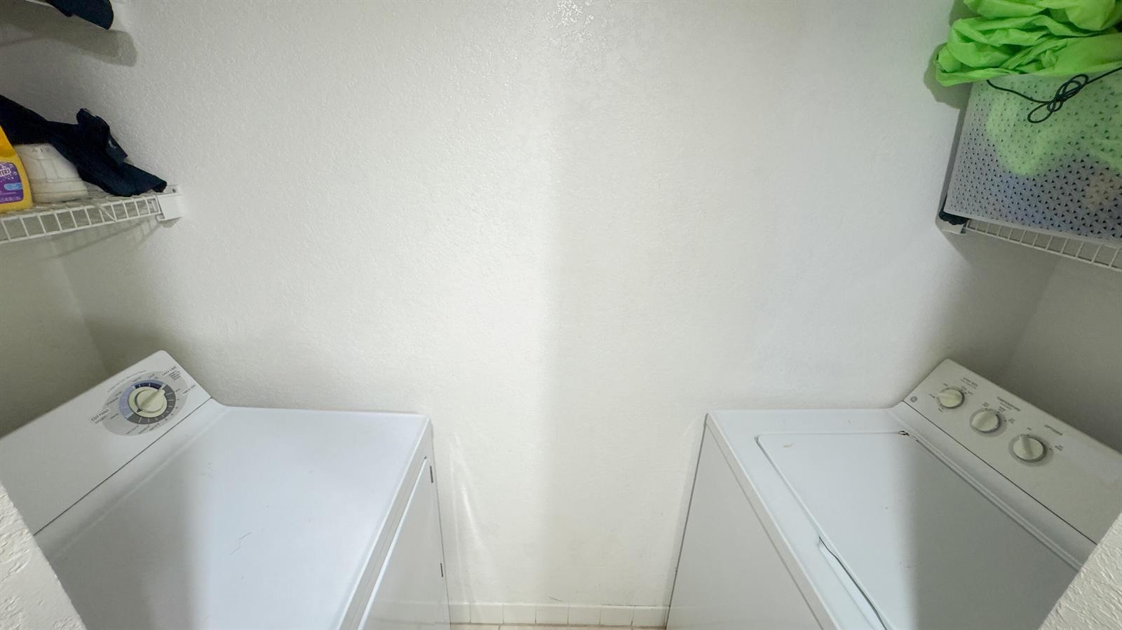 A laundry room features a white washer and dryer with wire shelving above — 407 Arabian Road, Palm Springs FL 33461, PALM SPRINGS, FL