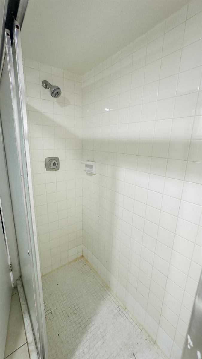 A walk-in shower with white square wall tiles, a glass door, and a showerhead — 407 Arabian Road, Palm Springs FL 33461, PALM SPRINGS, FL