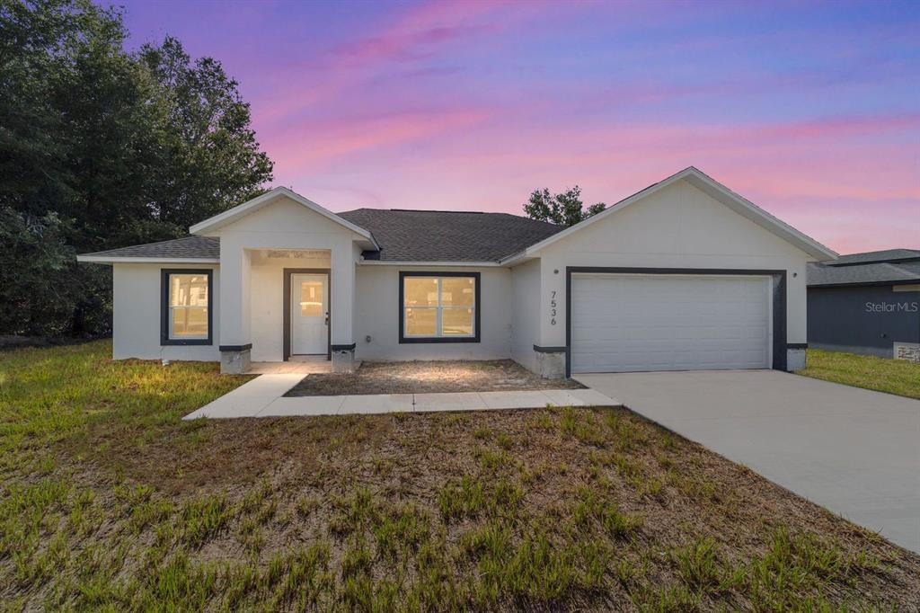 A single-story house with a white exterior, dark trim, and an attached two-car garage — 7536 SW 129TH PLACE, OCALA, FL