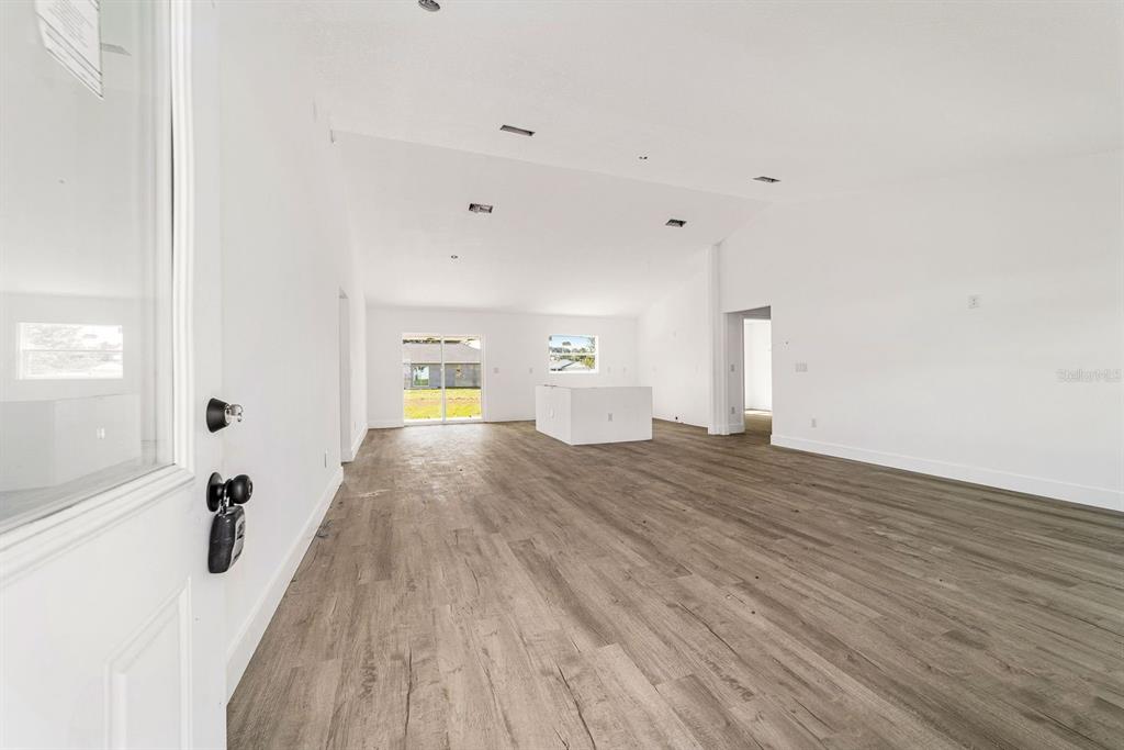 An open-concept living area features white walls, vaulted ceilings, and light wood-look flooring — 7536 SW 129TH PLACE, OCALA, FL