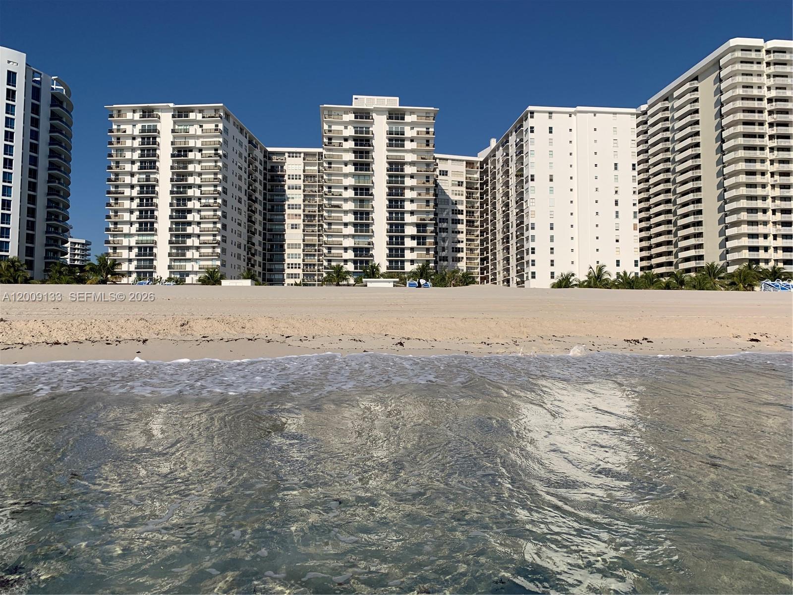 A view of tall white residential buildings situated directly behind a sandy beach — 6039 Collins Ave # 1510, Miami Beach FL 33140, MIAMI BEACH, FL