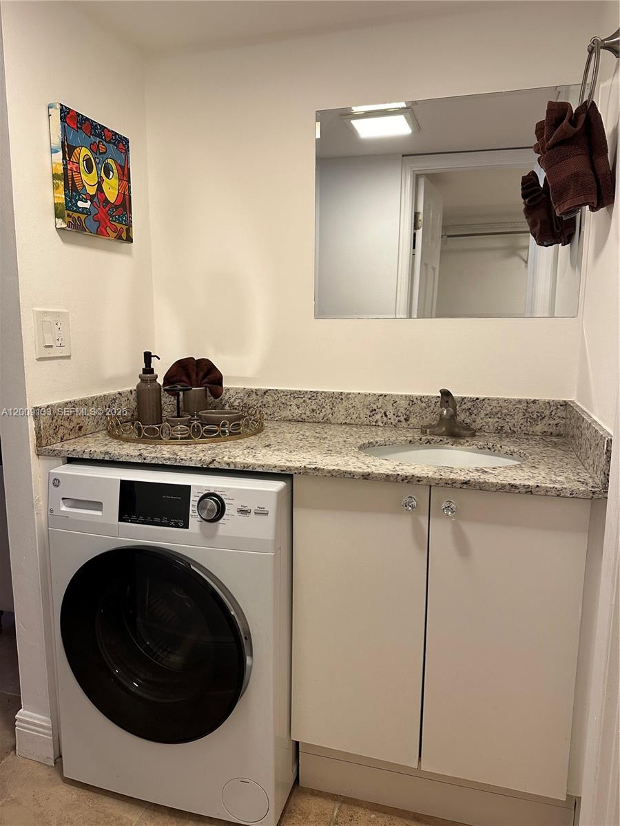 A laundry room features a front-loading washer, a granite countertop, and a small sink — 6039 Collins Ave # 1510, Miami Beach FL 33140, MIAMI BEACH, FL