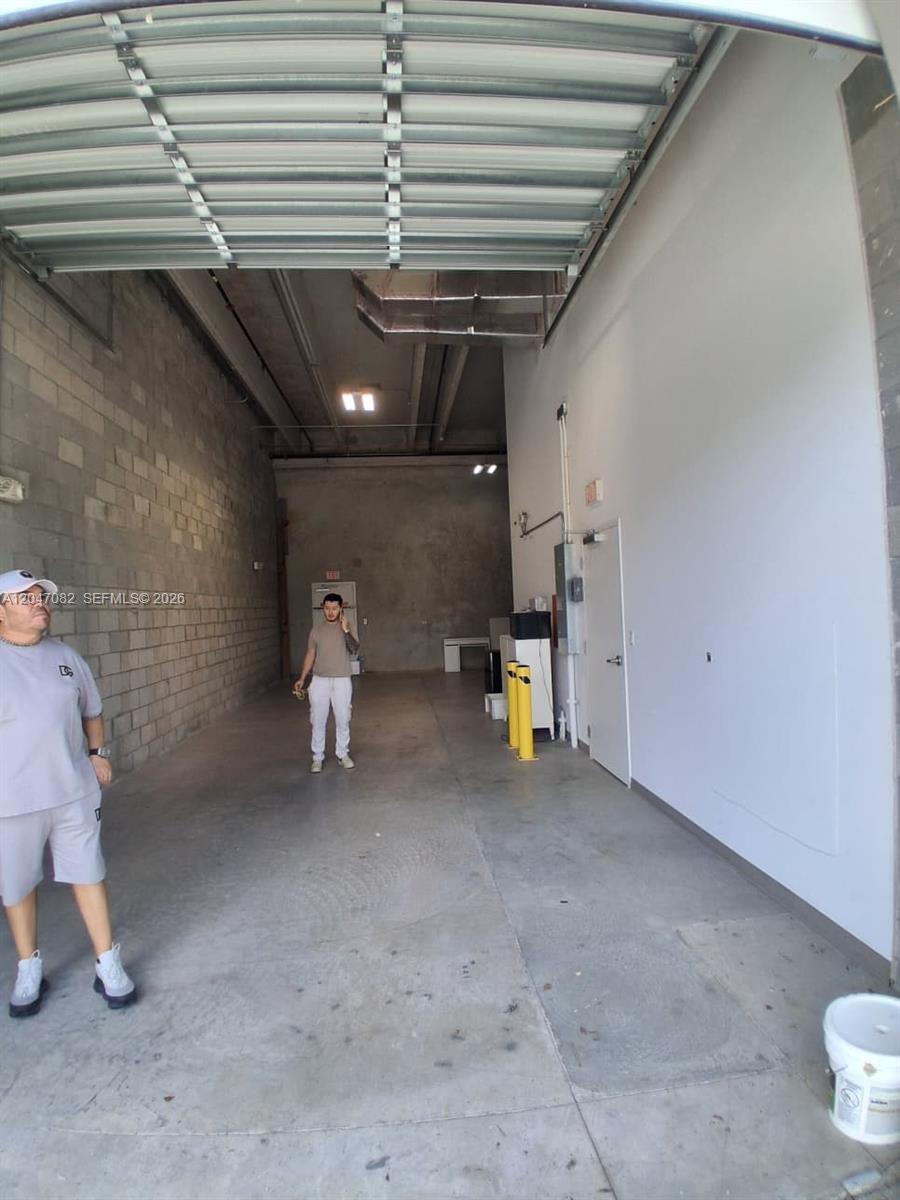 An interior view of a long, narrow industrial warehouse space with concrete walls and floors — SWEETWATER, FL