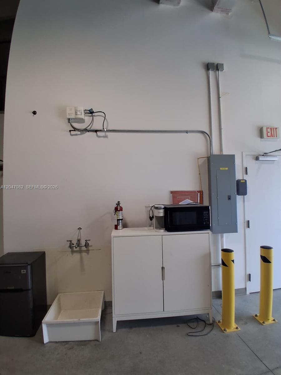 A utility area features a sink, a storage cabinet with a microwave, and electrical panels — SWEETWATER, FL