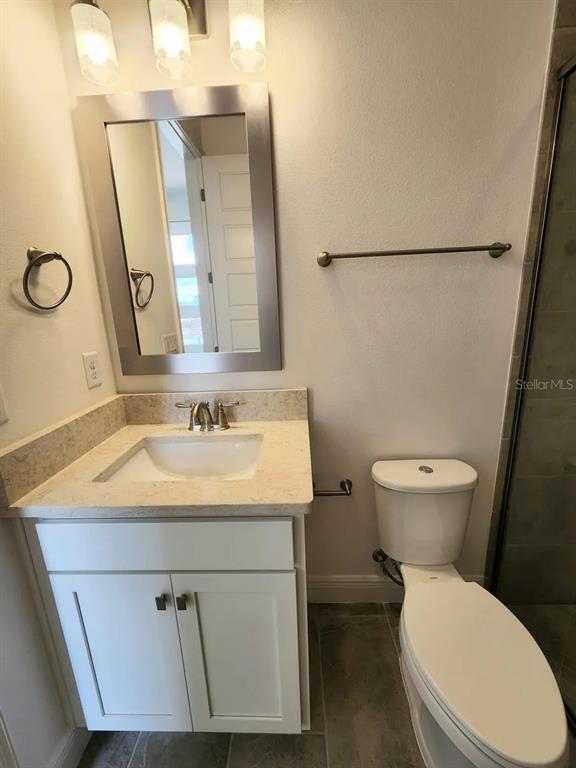 A bathroom features a white vanity with a stone countertop, a mirror, and a toilet — 13647 LARKTON LANE, ORLANDO, FL