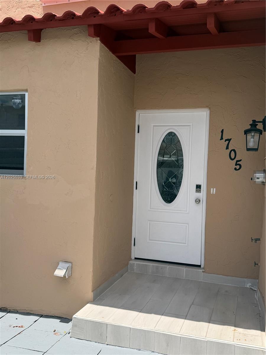 The exterior of a home features a white front door with an oval glass insert — 1705 W 57th St # 506, Hialeah FL 33012, HIALEAH, FL
