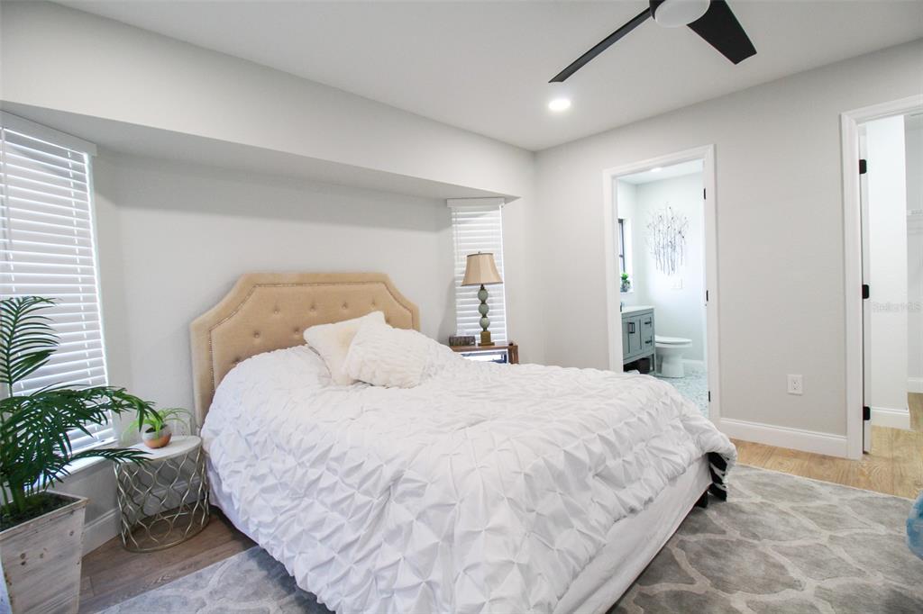 A bedroom features a tufted headboard, white textured bedding, a ceiling fan, and an attached bathroom — 4113 DURANT STREET, PORT CHARLOTTE, FL