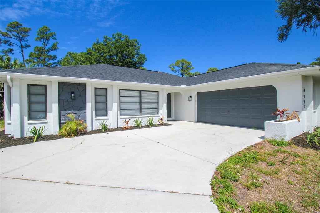 A single-story house with a white exterior, dark gray garage door, and a concrete driveway — 4113 DURANT STREET, PORT CHARLOTTE, FL