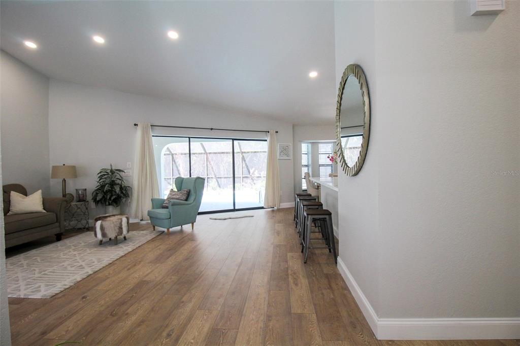 A living room with wood-look flooring, a teal armchair, and a breakfast bar with stools — 4113 DURANT STREET, PORT CHARLOTTE, FL