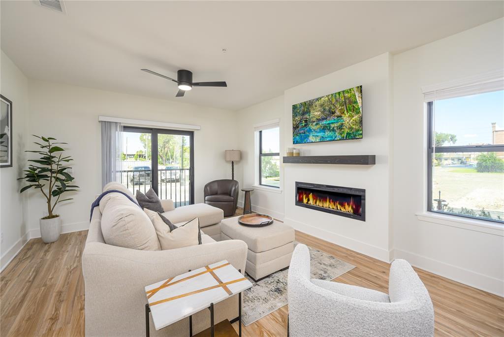 A living room features a sectional sofa, an electric fireplace, a wall-mounted television, and wood-look flooring — 419 SE 1ST AVENUE UNIT 103, OCALA, FL