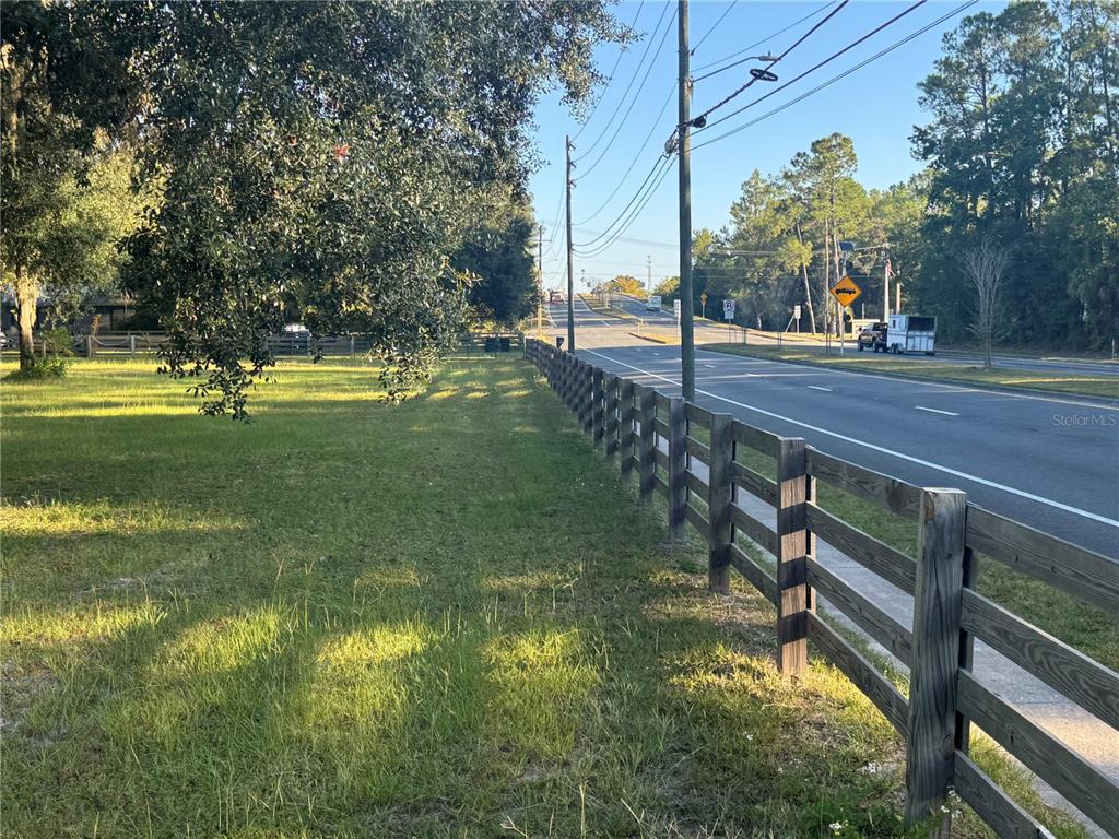 A grassy lot borders a paved road and is enclosed by a wooden fence — TBD NE US HIGHWAY 301, WALDO, FL