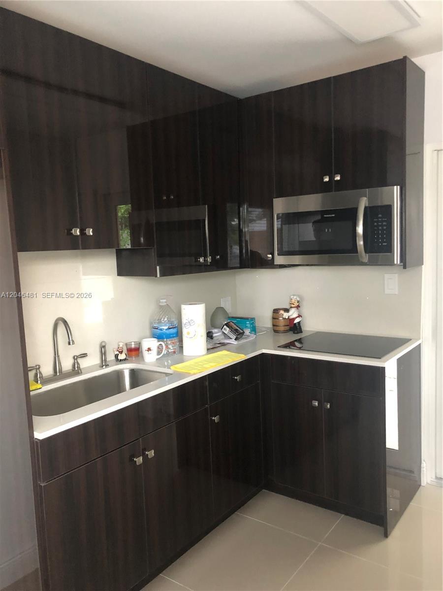 A kitchen features dark wood cabinets, a stainless steel microwave, and a white countertop — 4440 NW 3rd St # 1, Miami FL 33126, MIAMI, FL