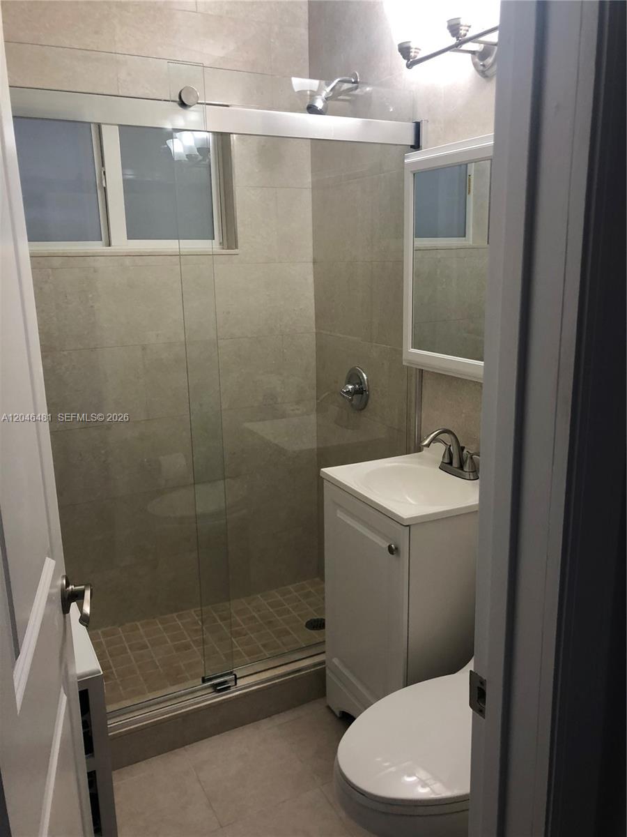 A small bathroom features a glass-enclosed shower, a pedestal sink, and light-colored tile walls — 4440 NW 3rd St # 1, Miami FL 33126, MIAMI, FL