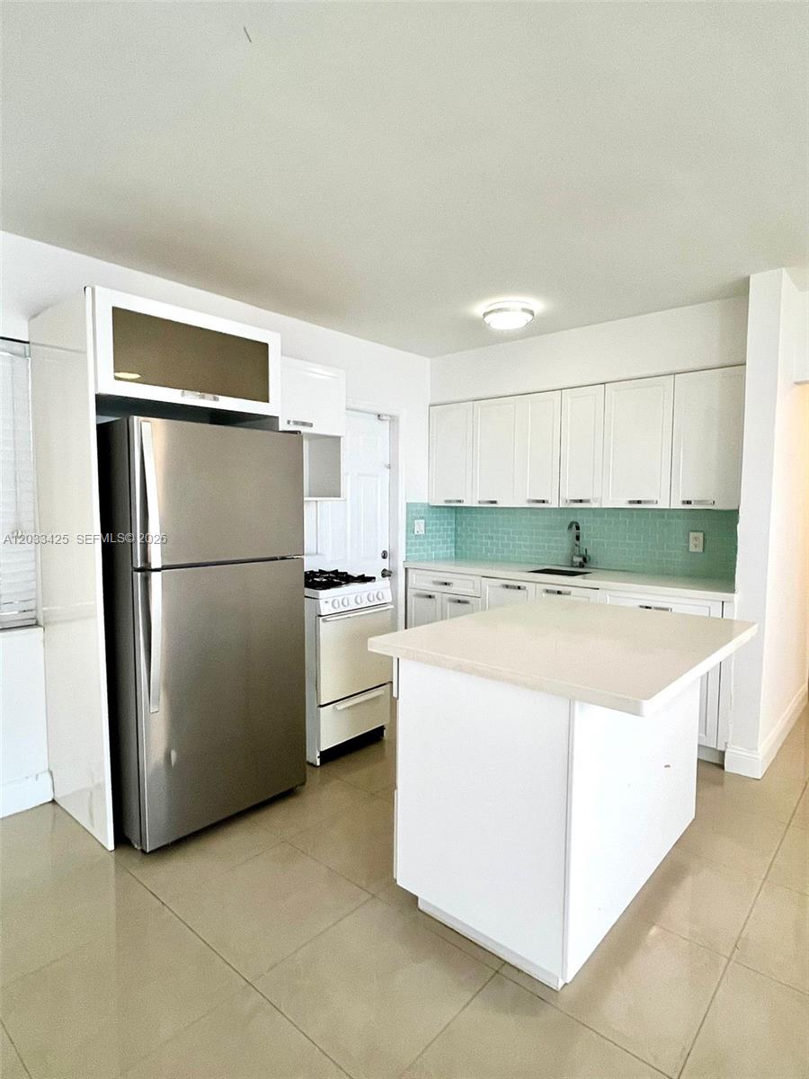 A kitchen features white cabinetry, a stainless steel refrigerator, a white stove, and a central island — 2031 Jackson St # 3, Hollywood FL 33020, HOLLYWOOD, FL