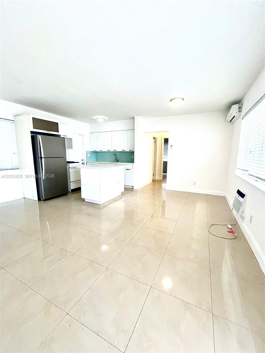 A kitchen with white cabinets and stainless steel appliances opens into a tiled living area — 2031 Jackson St # 3, Hollywood FL 33020, HOLLYWOOD, FL