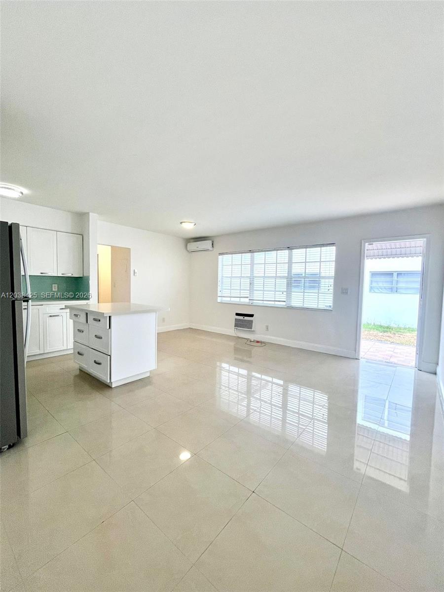 A bright kitchen and living area features white cabinetry, a center island, and tile flooring — 2031 Jackson St # 3, Hollywood FL 33020, HOLLYWOOD, FL