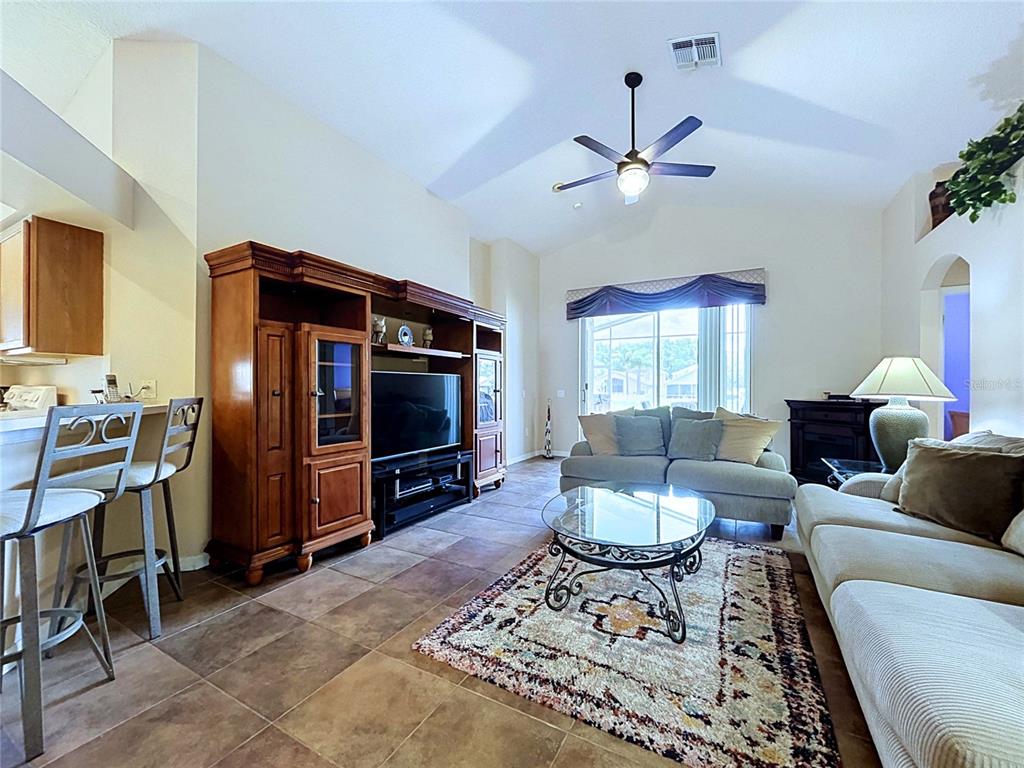 A living room features tile flooring, a large wooden entertainment center, and two sofas — 4849 WESSEX WAY, LAND O LAKES, FL