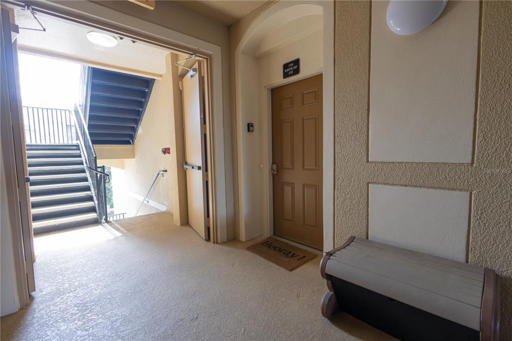 An apartment entryway features a brown door, a staircase, and a small bench — 2784 ALMATON LOOP UNIT 301, KISSIMMEE, FL