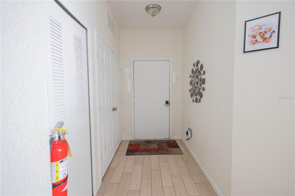 A bright entryway features light tile flooring, a white front door, and a fire extinguisher — 2784 ALMATON LOOP UNIT 301, KISSIMMEE, FL