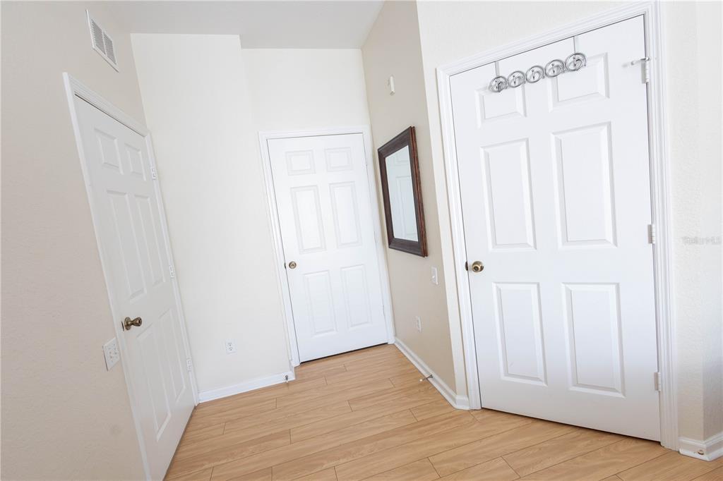 A hallway features light wood-look flooring, beige walls, and three white paneled doors — 2784 ALMATON LOOP UNIT 301, KISSIMMEE, FL