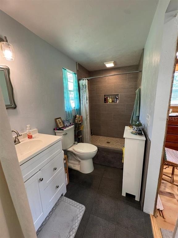 A bathroom features a white vanity, a toilet, and a tiled walk-in shower — 3725 SW 162ND STREET, ARCHER, FL