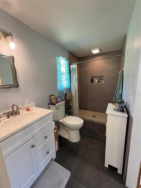 A bathroom features a white vanity, a toilet, and a walk-in shower with tiled walls — 3725 SW 162ND STREET, ARCHER, FL