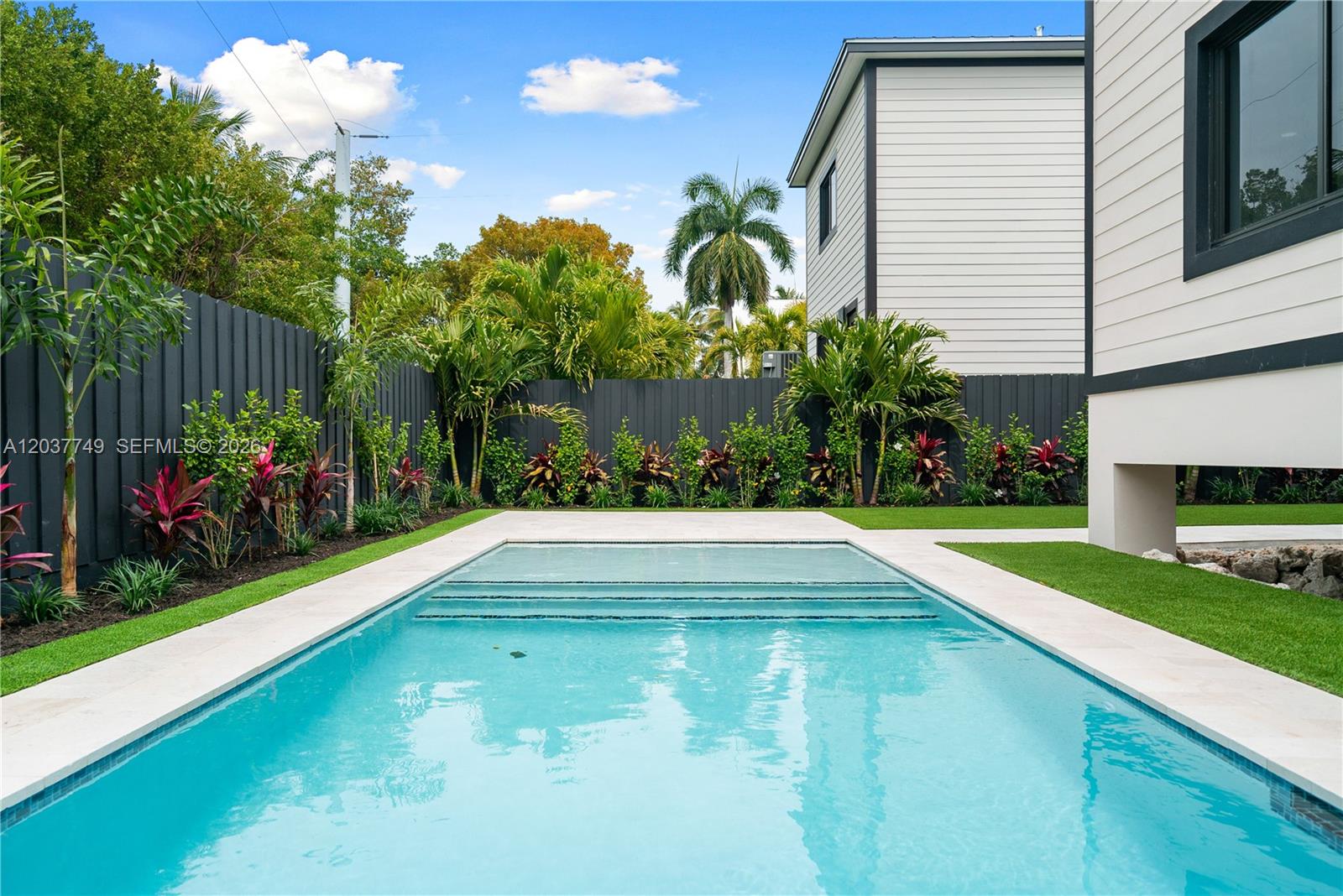 A rectangular swimming pool sits in a backyard with a dark fence and landscaping — 17 Coral Way, Key Largo FL 33037, KEY LARGO, FL