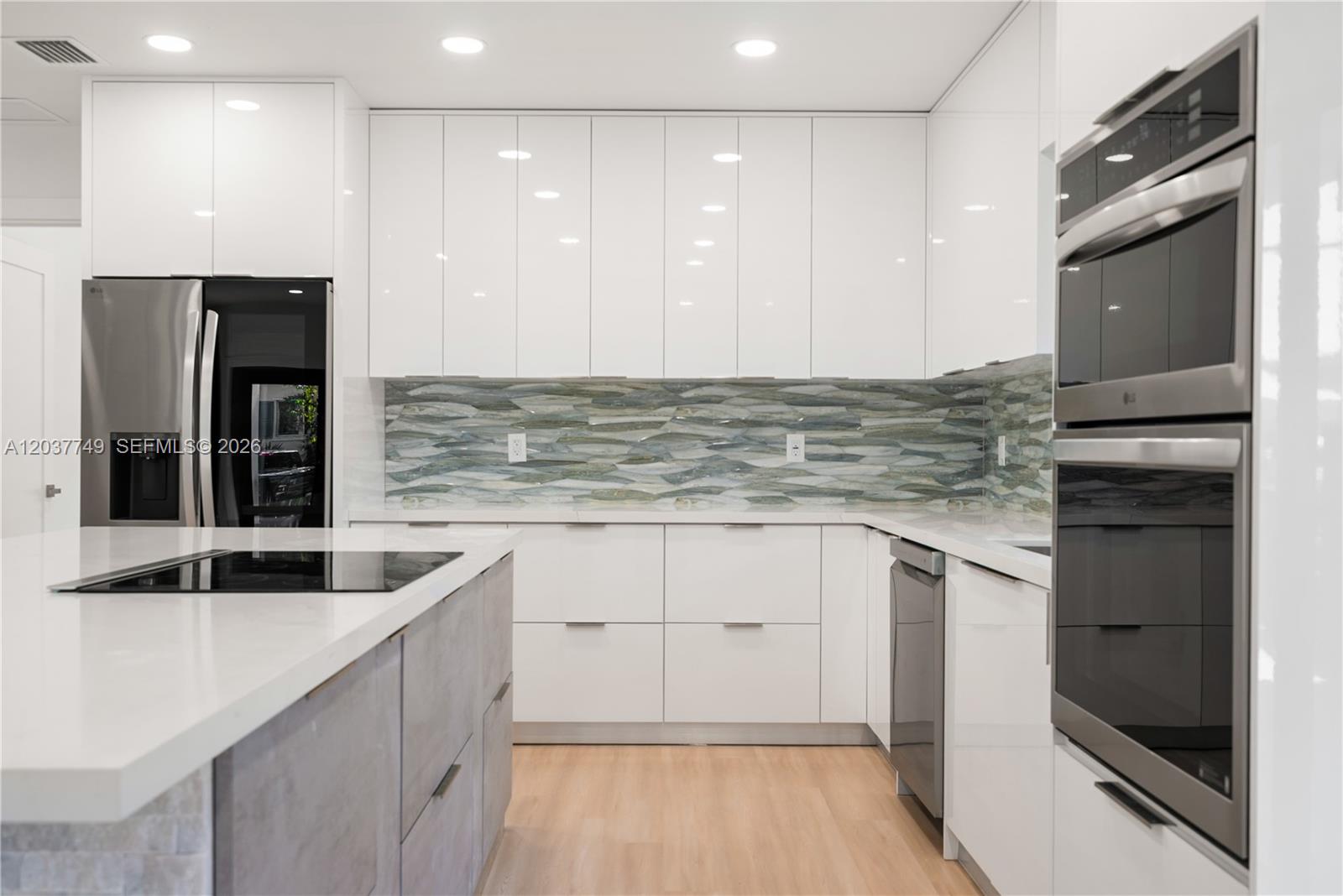 A modern kitchen features white cabinetry, a gray island, stainless steel appliances, and patterned backsplash — 17 Coral Way, Key Largo FL 33037, KEY LARGO, FL
