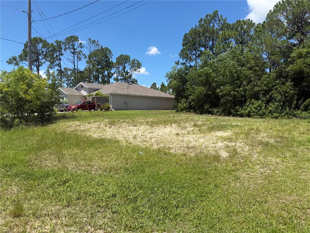 A vacant, grassy lot sits in front of a suburban house under a blue sky — 2850 NW 28TH AVENUE, CAPE CORAL, FL