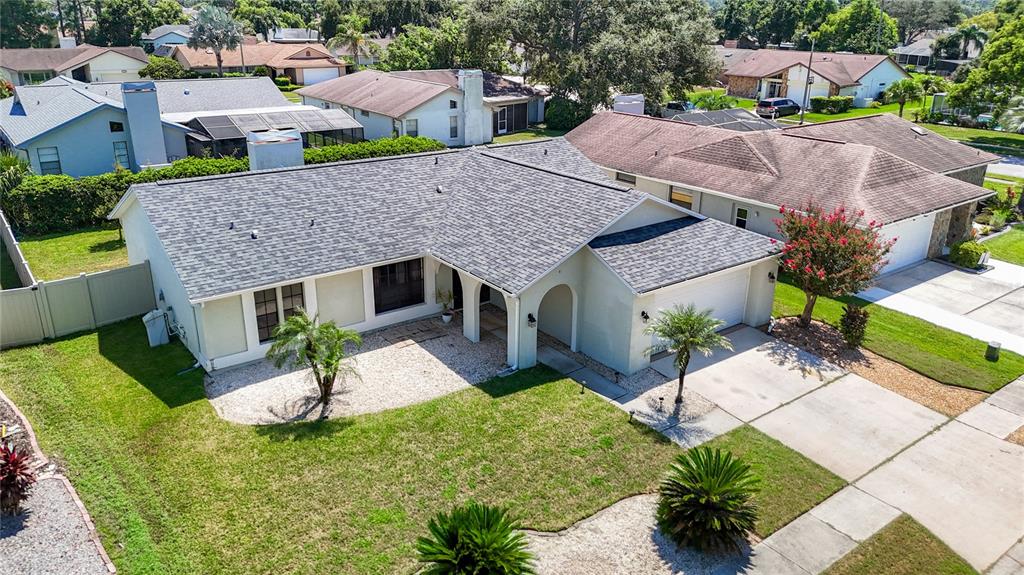 An aerial view of a single-story house with a gray shingled roof and a driveway — 9902 STEPHENSON DRIVE, NEW PORT RICHEY, FL