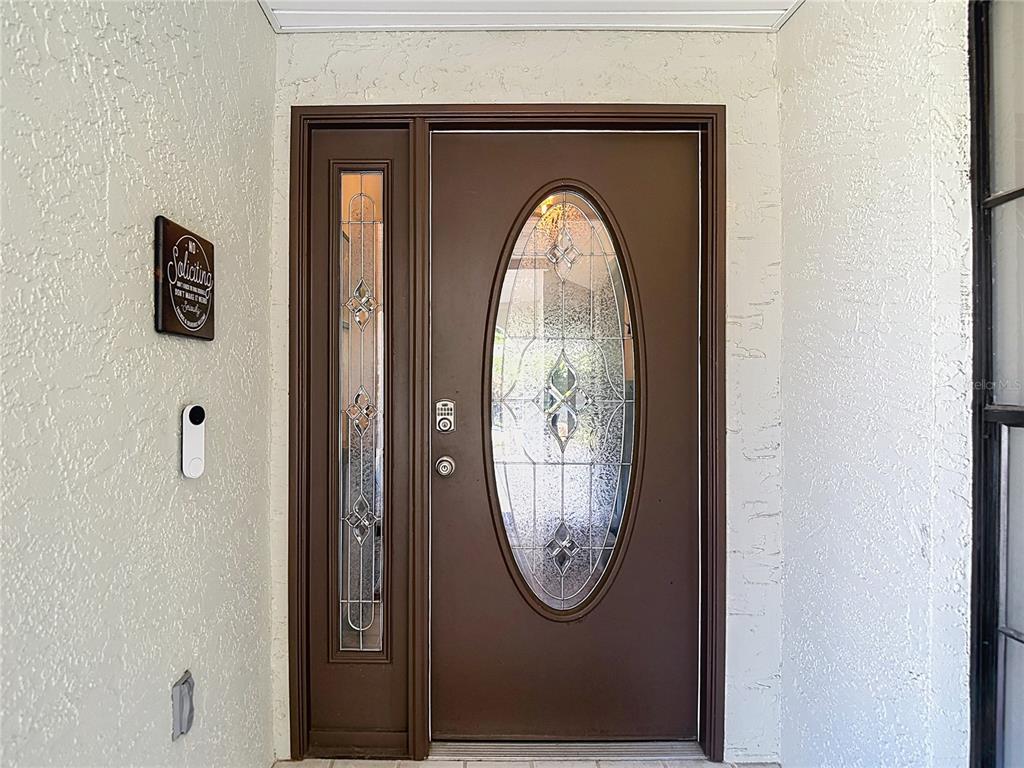 A brown front door with an oval glass insert and a matching side light window — 9902 STEPHENSON DRIVE, NEW PORT RICHEY, FL